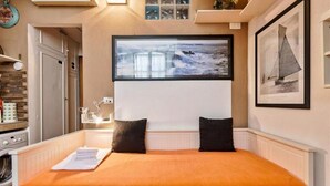 Un dormitorio con cama, ventana con vista al mar y un cuadro en la pared.