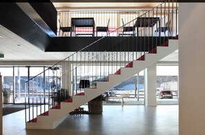 Un interior moderno con una escalera, ventanas amplias y vistas a un paisaje nevado.