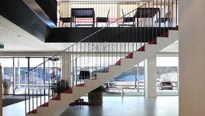 A modern interior with a staircase, large windows, and a view of a snowy landscape.