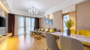 A modern living room with a sofa, a dining table with chairs, a coffee table, and a TV. - Manhattan Langde Apartment (Guangzhou)