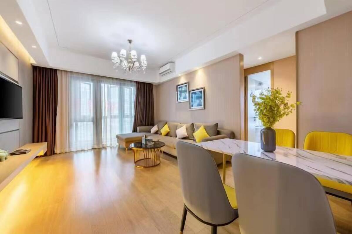 Uma sala de estar moderna com um sofá, uma mesa de jantar com cadeiras, uma mesa de centro e uma televisão.