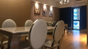 A modern dining area with a long table and chairs, a sofa, and wall-mounted artwork. - Manhattan Langde Apartment (Guangzhou)