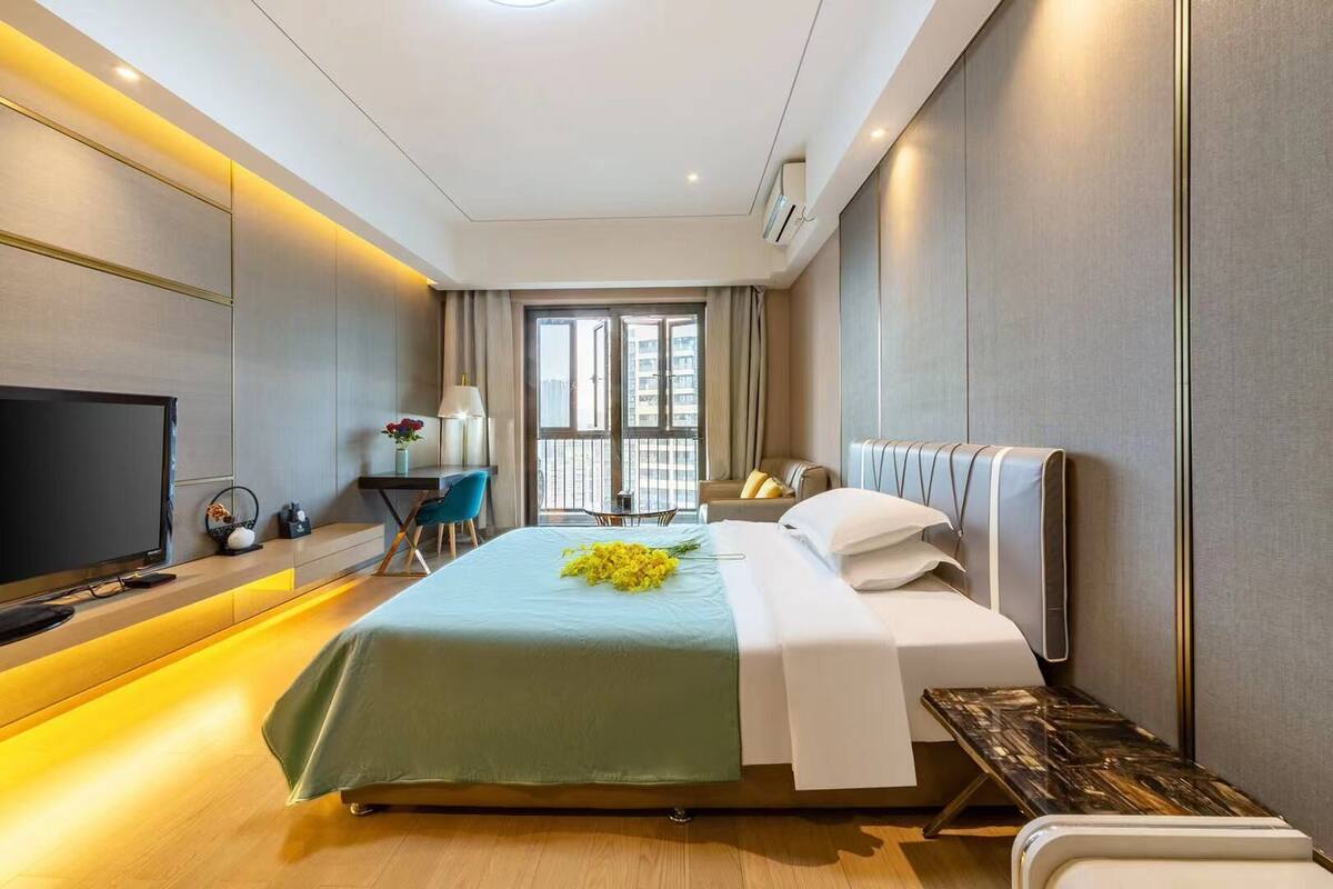 Quarto de hotel moderno com uma cama grande, uma mesa, uma TV e uma varanda com vista.