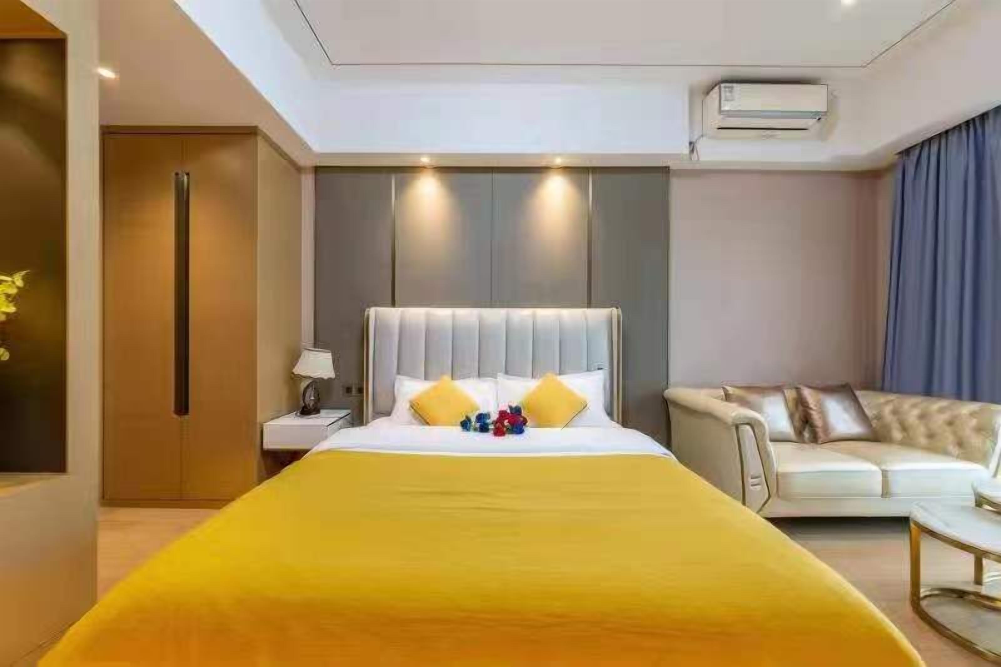 Quarto de hotel com uma cama grande, um sofá, uma mesa de cabeceira e um aparelho de ar condicionado.