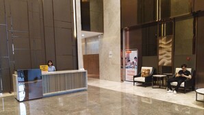 A reception area with a marble floor, a reception desk, and two seating areas with chairs and tables. - Manhattan Langde Apartment (Guangzhou)