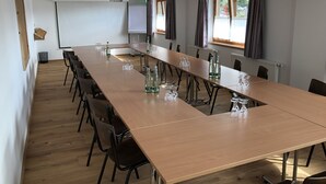 Un salón de conferencias con una mesa larga, sillas y una pantalla para proyector.