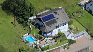 Eine Vogelperspektive auf ein Haus mit Swimmingpool, Solaranlage und umzäunter Garten.