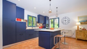 A modern kitchen with blue cabinets, a central island, and a large window. - Stunning home in Nessa (Nessa)