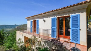 A two-story building with blue shutters, a balcony with a metal railing, and a view of the countryside. - Stunning home in Nessa (Nessa)