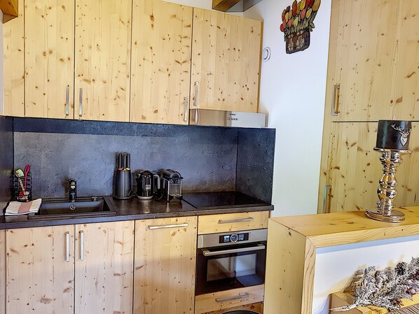 A kitchen with wooden cabinets, a black countertop, and a built-in oven.