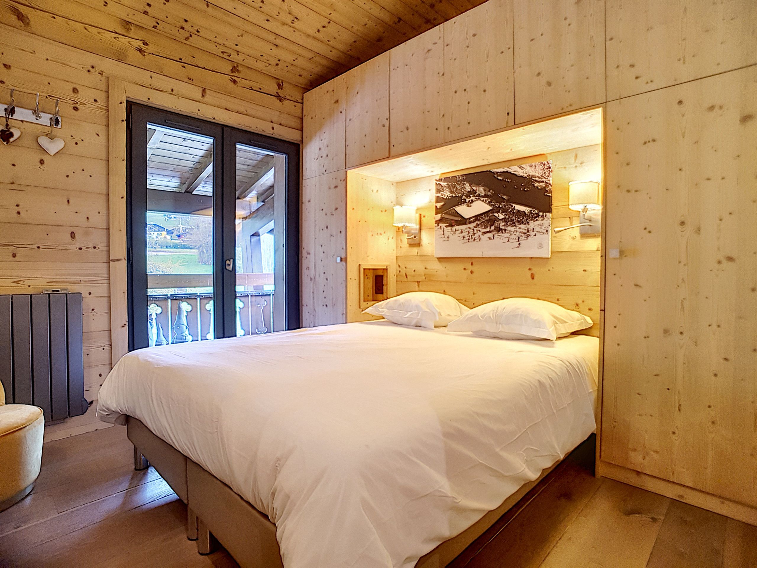 A wooden room with a bed, a window, and a door.