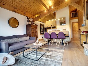 A cozy living room with a sofa, a coffee table, and a dining area with chairs.
