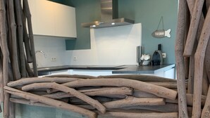 Eine rustikale Küche mit einer Holzkonstruktion im Vordergrund, einer Kerze in einer Kiste und einem modernen Herd im Hintergrund.