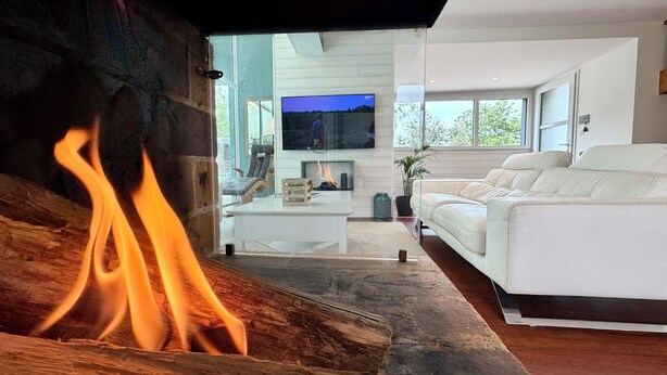 Ein modernes Wohnzimmer mit Kamin, einem weißen Sofa und einem Fernseher.