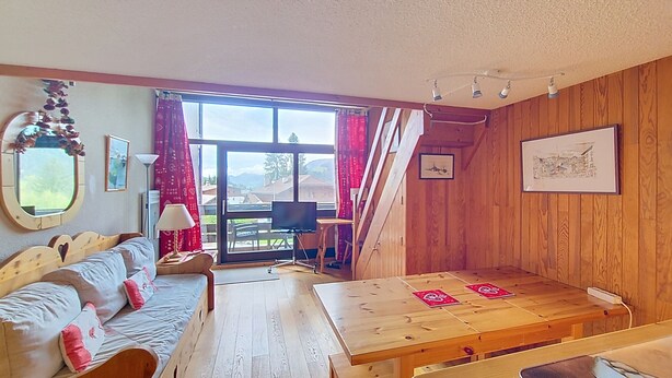 A cozy room with a wooden floor, a sofa, a table, and a window with curtains. - 1 RR6183 - (Megève)