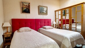A room with two beds, a red headboard, a wooden wardrobe, and two paintings on the wall. - 1 RR6183 - (Megève)