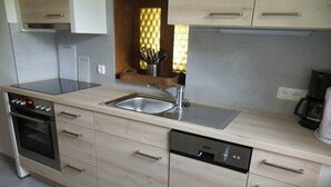 Eine moderne Küche mit Einbauofen, Geschirrspüler und Spüle aus Edelstahl.