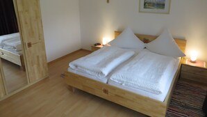 Ein ordentlich bezogenes Bett mit weißen Leinen, einem hölzernen Kopfteil und zwei Nachttischlampen.
