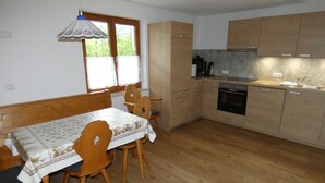 Eine kleine Küche mit Holzausstattung, einem eingebauten Backofen und einem Esstisch mit Stühlen.