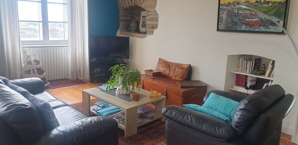 A living room with a sofa, a coffee table, a bookshelf, and a television. - Drellach's house (Le Conquet)
