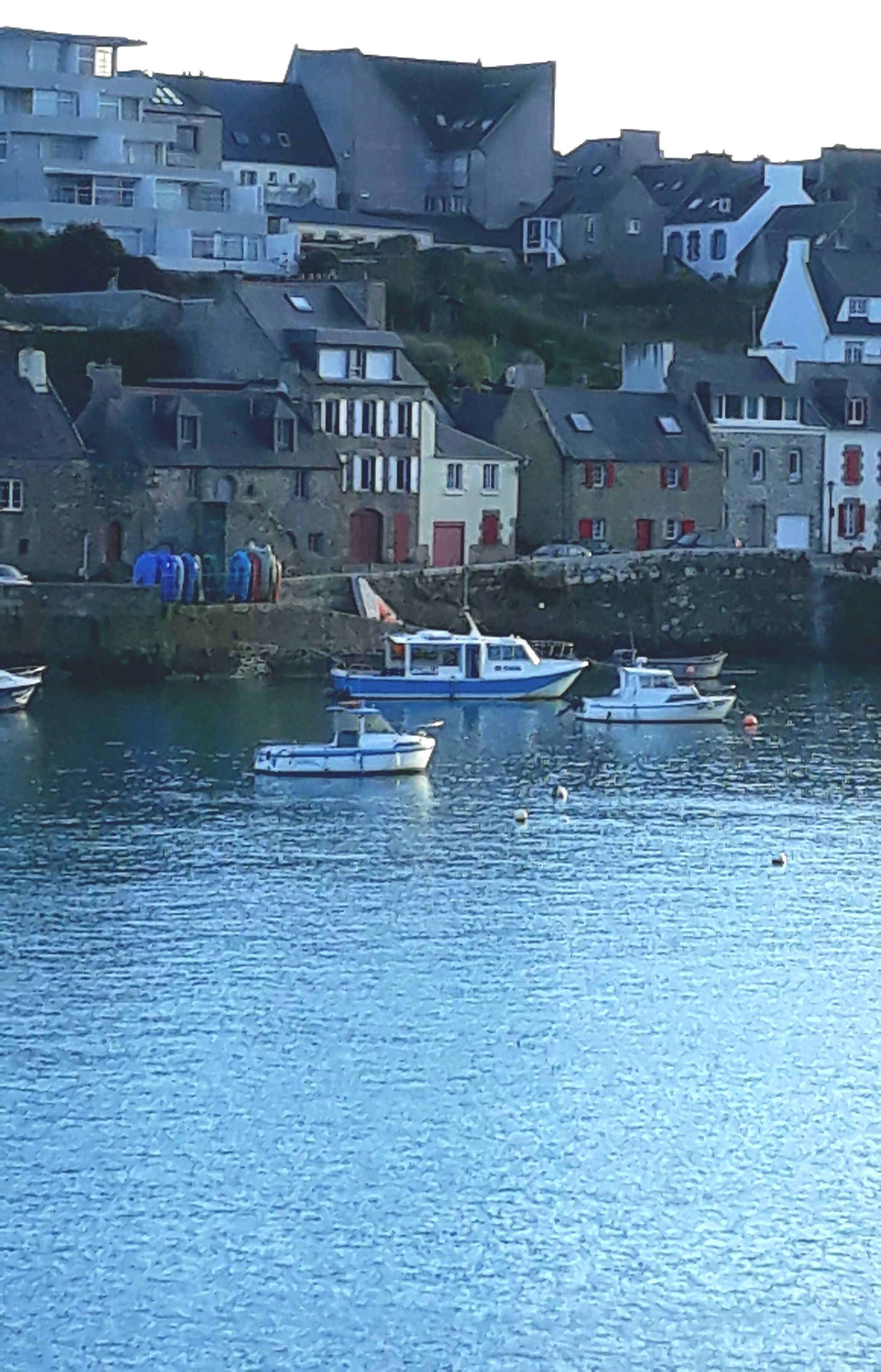 A harbor with several boats docked near buildings with red shutters.
