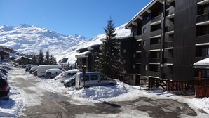 A snow-covered parking lot with several cars and a building with multiple balconies. - Les Menuires, charming renovated two-room apartment at the foot of the slopes    (Les Belleville)