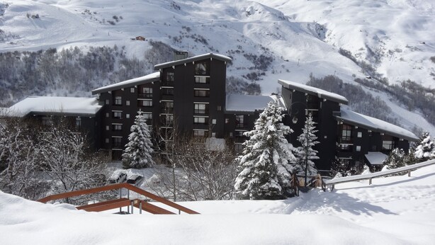 A snow-covered mountain resort with a large building featuring multiple balconies and a ski slope in the background. - Les Menuires, charming renovated two-room apartment at the foot of the slopes    (Les Belleville)