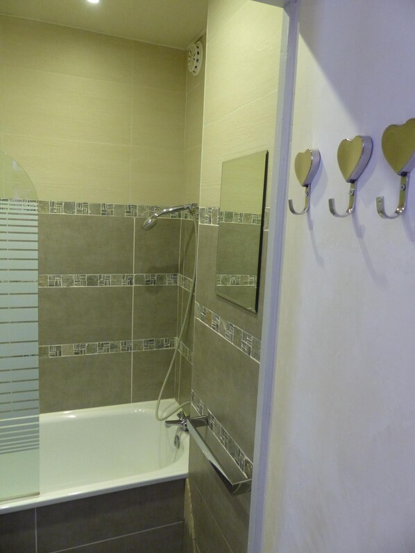 A bathroom with a bathtub, a shower, and a mirror.