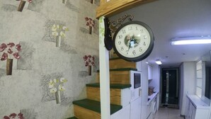 A staircase with green carpeted steps leading to a landing with a wall-mounted clock. - Gangnam Residence 4 (Seoul)