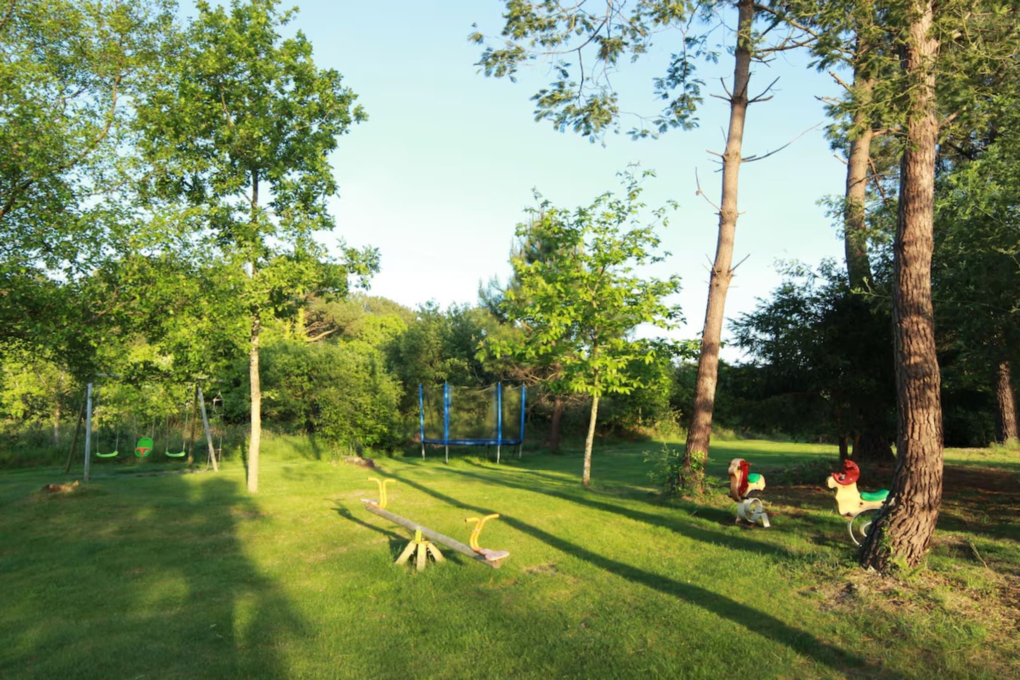 Un parc verdoyant avec des arbres, une balançoire et un jeu de bascule.