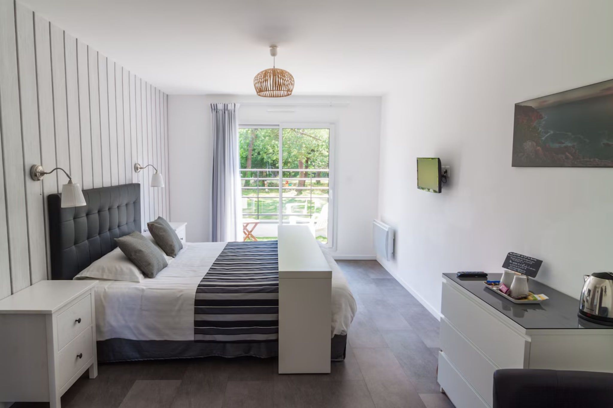 Een moderne slaapkamer met een bed, nachtkastjes, een bureau en uitzicht op het omliggende landschap.