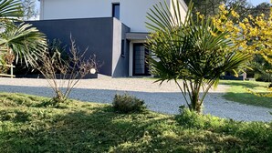 A modern two-story house with a flat roof, a small front porch, and a gravel driveway.