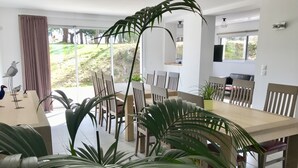 A dining area with a large table, chairs, and potted plants.
