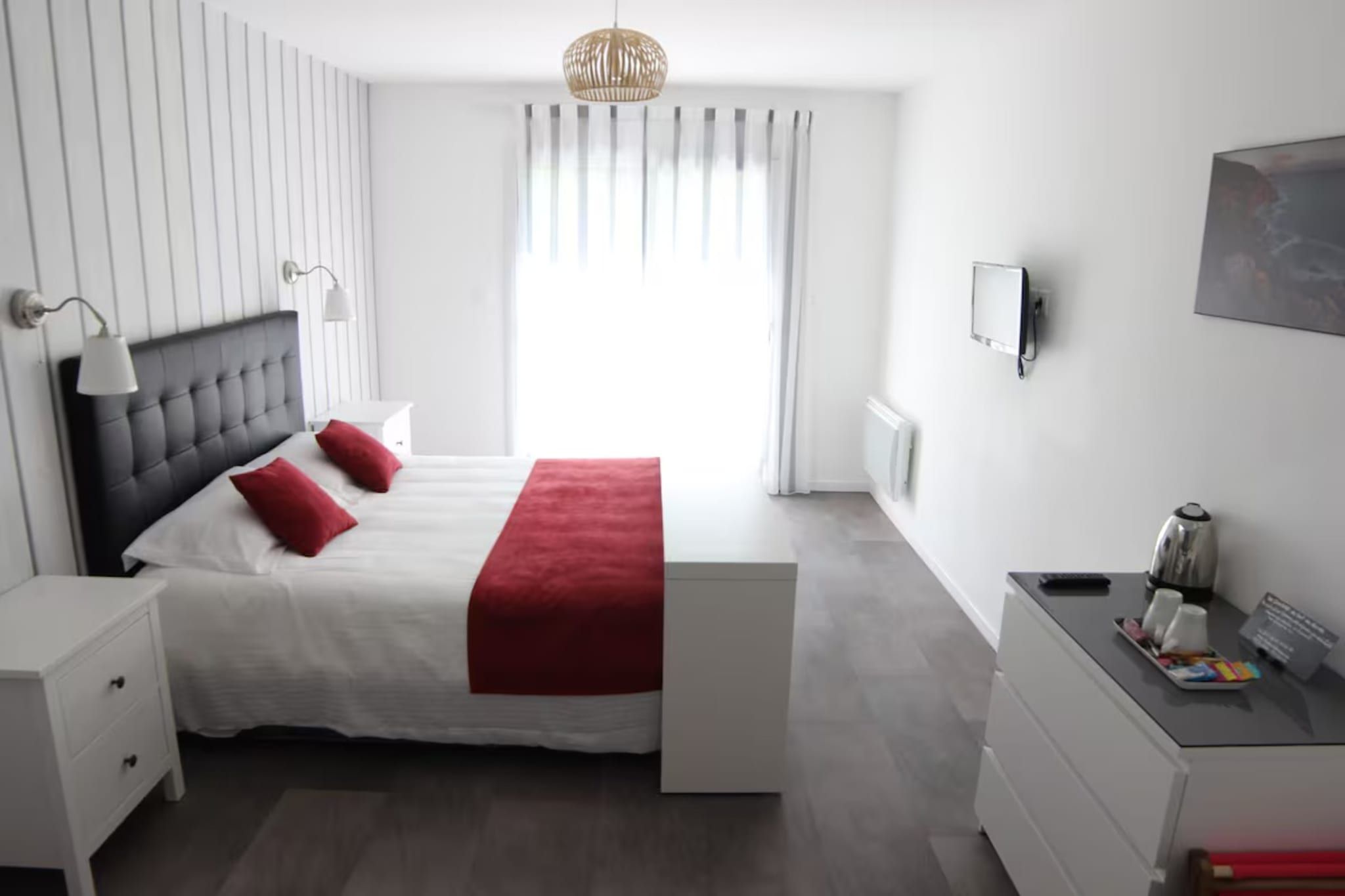 Ein modernes Schlafzimmer mit einem Bett, Nachttischen, einem Schreibtisch und einem Fenster mit Vorhängen.