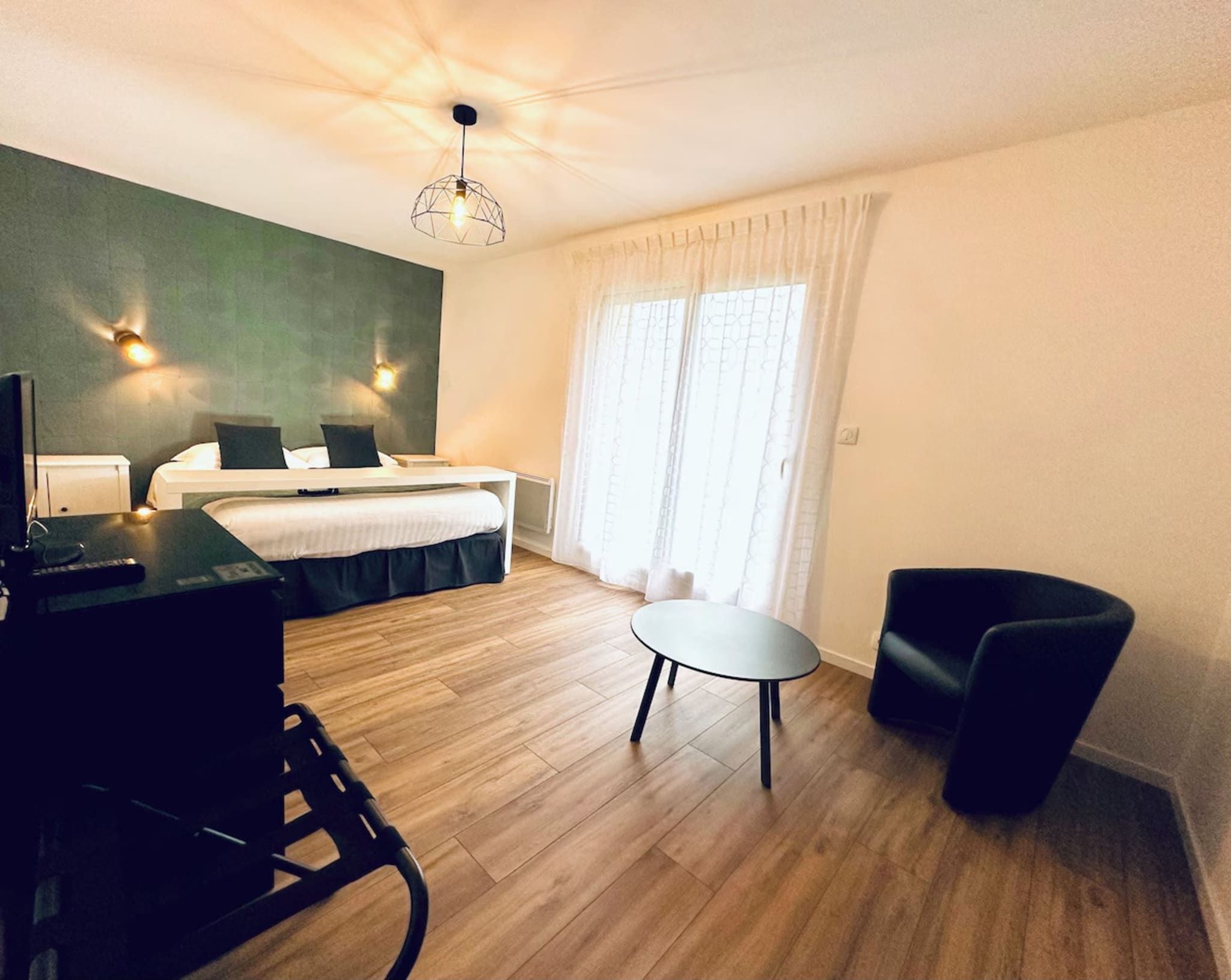 A hotel room with a bed, a desk, a chair, and a small table.