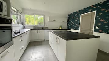 A modern kitchen with white cabinetry, a large island, and a window providing natural light.