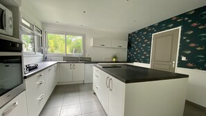 A modern kitchen with white cabinetry, a black countertop, and a window providing natural light.