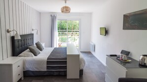 A modern bedroom with a bed, bedside tables, a desk, and a view of the outdoors.
