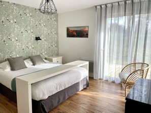 A bedroom with a bed, a nightstand, a chair, a painting, and a window with curtains.