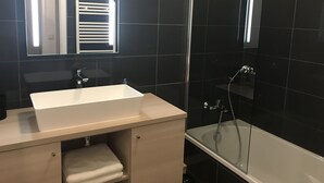 Ein modernes Badezimmer mit Waschbecken, Spiegel und einer Duschkabine.