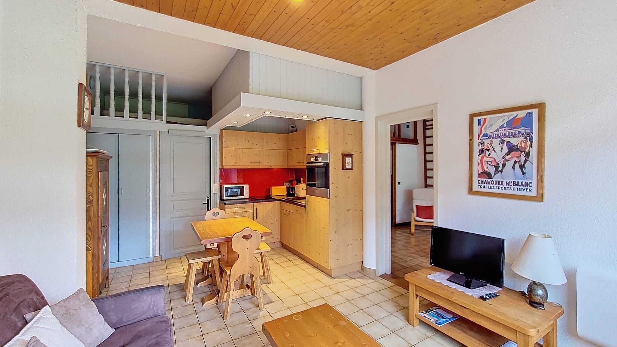 A compact living space with a dining area, kitchenette, and a television.