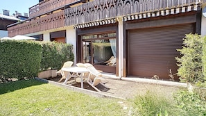 A residential building with a balcony, a sliding glass door, and a patio area with outdoor furniture.