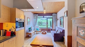 A compact kitchen with modern appliances, a dining area with a wooden table, and a seating area with a sofa and armchairs.