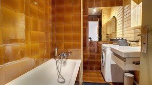 Ein Badezimmer mit einer Badewanne, einer Waschmaschine und einem Spiegel.