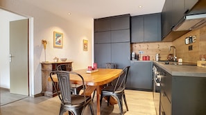 A compact kitchen with a dining area, featuring a wooden table, metal chairs, and a built-in oven.