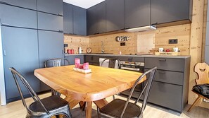 A modern kitchen with a wooden dining table, chairs, and built-in cabinets.