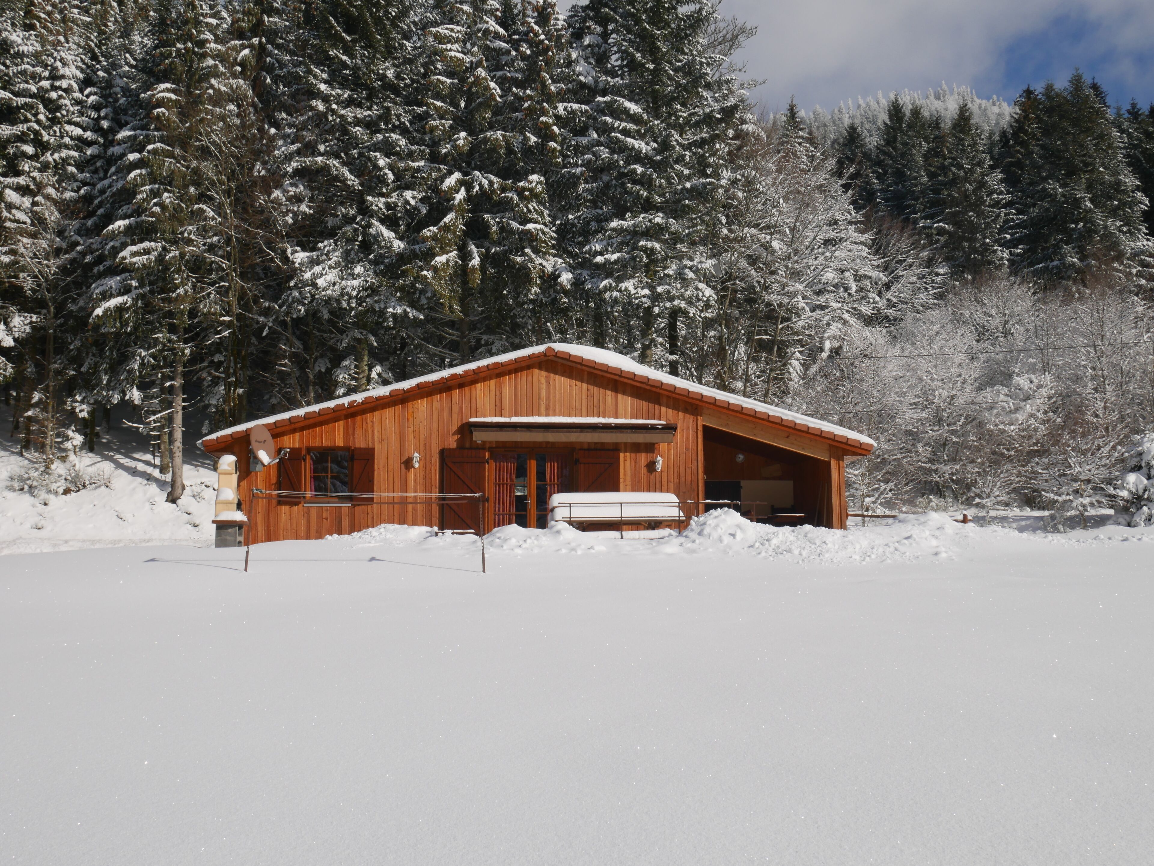 Une cabane en bois, dotée d’un toit en pente, entourée d’arbres couverts de neige.