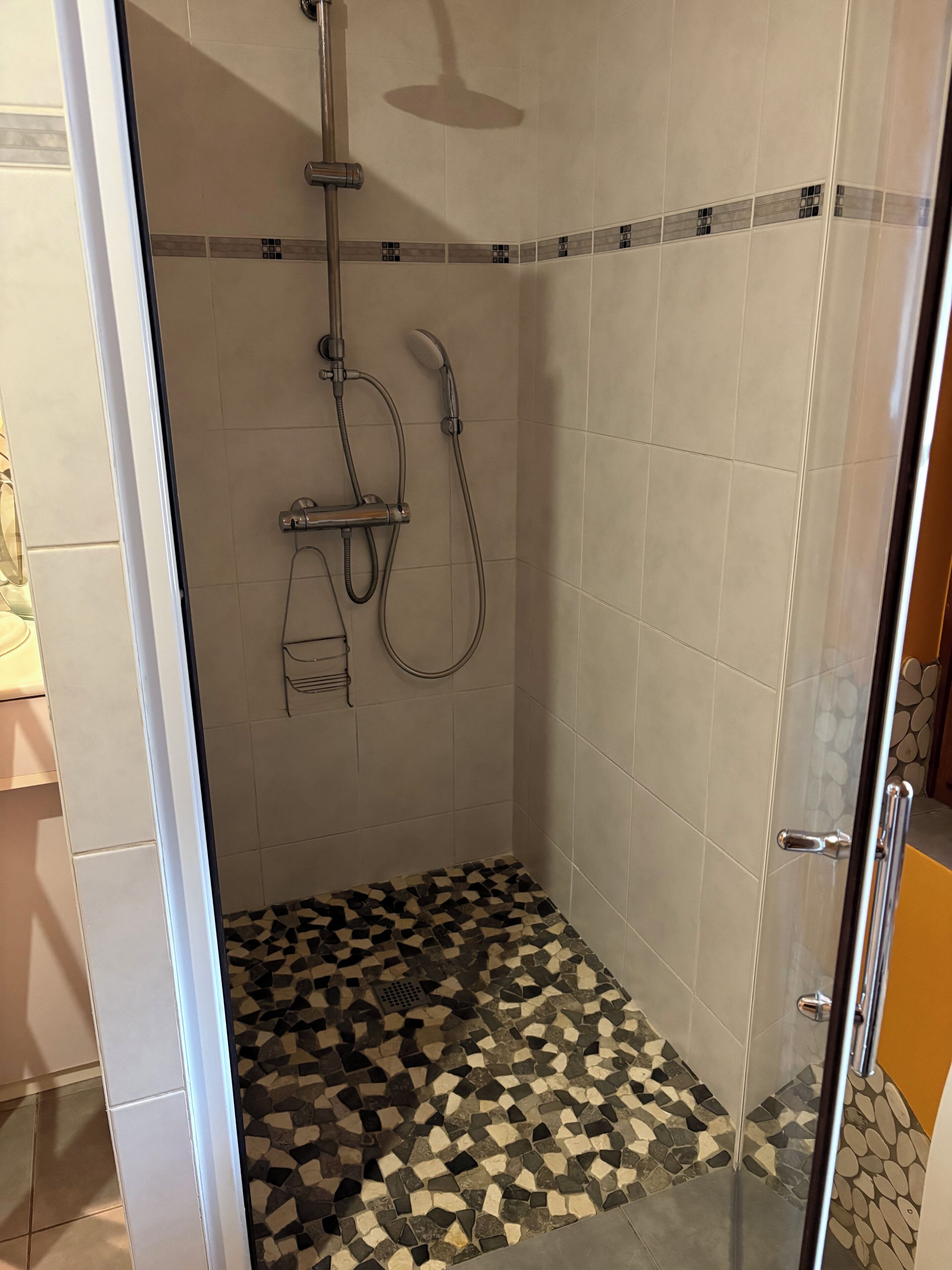 Doccia con pavimento piastrellato, soffione e doccetta.