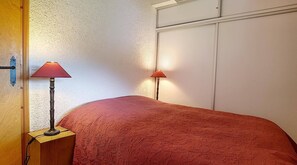 A bedroom with a bed, two bedside lamps, a wooden door, and a white wall.