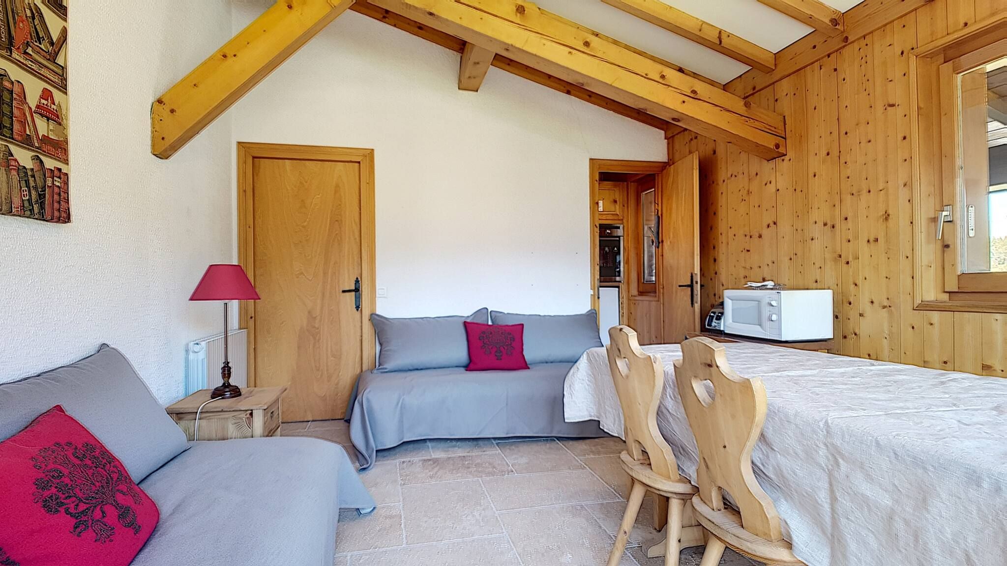 Une pièce confortable avec un lit, une petite table avec une lampe et un coin cuisine.